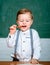 Portrait of thinker preschooler in classroom. Cute child preschooler in classroom near blackboard desk. Educational