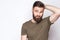 Portrait of thinking bearded man with dark green t shirt against light gray background.