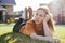 Portrait of thinking teen girl lying on sunny green grass of cottage village on background