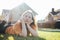 Portrait of thinking teen girl lying on sunny green grass of cottage village on background