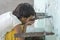 Portrait of thirsty Indian girl drinks water from the outdoor tap on the street in Rishikesh, India