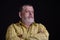 Portrait of a thoughtful Caucasian, bearded senior man in yellow shirt