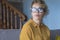 Portrait of thoughtful young adult woman with eyewear sitting on the sofa at home looking outside. Hope and dreams concept people