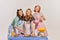 Portrait of three beautiful women, housewives posing in the kitchen isolated over grey background