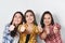 Portrait of three beautiful young happy females smiling joyfully showing thumbs up on white