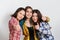 Portrait of three beautiful young happy females smiling joyfully showing thumbs up on white