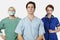 Portrait of three confident medical practitioners against gray background