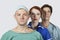 Portrait of three confident medical practitioners against gray background