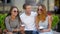 Portrait of three friends drinking coffee sitting on the bench outdoors in the city during warm summer day