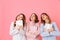 Portrait of three happy girls 20s wearing colorful striped pyjamas looking upward with gift boxes in hands, isolated over pink ba