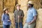 Portrait of three positive farmers standing near the haystacks and having an interesting conversation