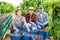 Portrait of three positive hardworking farmers with cherries collected in buckets and crates