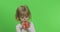 Portrait of three years old blonde girl plays on toy pipe on green background