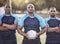 Portrait three young african american rugby players holding a rugby ball while standing outside on the field. Black men