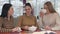 Portrait of three young beautiful caucasian woman sitting at the table in cafe and talking. Charming ladies resting in