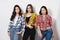 Portrait of three young beautiful slender girls women in plaid shirts red, yellow and blue on white background