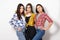 portrait of three young beautiful slender girls women in plaid shirts red, yellow and blue on white background