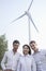 Portrait of three young business people standing in front of a wind turbine, looking at camera