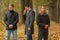 Portrait of three young men in autumn park, one