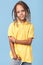 Portrait of timid little boy with african dreads posing over blue background.