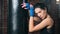 Portrait of tired beautiful fighter woman posing with punching bag looking at camera medium close-up