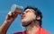 Portrait of a tired cyclist in retro helmet drinks water from cup.