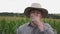 Portrait of tired male farmer yawning against the blurred background of corn field. Exhausted sleepy worker standing in