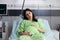 Portrait of tired pregnant person sitting in hospital ward bed