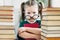 Portrait of tired of reading little girl with big round glasses on her nose among books. Kids education concept