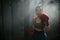 Portrait of tired sweaty female boxer standing in smoke looking at the camera