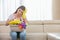 Portrait of tired woman with basket of cleaning supplies sitting on sofa at home