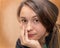 Portrait of a tired young woman 30 years old without makeup head on her hand looks into the lens on a brown background