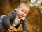 Portrait of toddler little blond boy creeping at the autumn park. Copy space