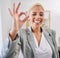 Portrait, tongue and emoji with a business black woman winking in her office at work to gesture a perfect hand sign