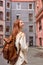 Portrait of tourist redhead woman taking photo of architecture on retro film camera