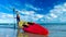 Portrait of a tourist surfer with paddleboard at the tropical beach island on a sunny day. A sportsman with SUP board on vacation