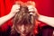 Portrait of tousled disheveled middle-aged woman looking like a madwoman on red background in studio. Actress during the