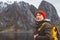 Portrait traveler man with a yellow backpack wearing a red hat on the shore on the background of mountain and lake