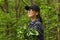 Portrait of traveler smiling young woman in black cap and glasses breathing fresh air in the green spring forest.