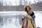 Portrait of a travelling woman in winter clothes standing in front of the lake in the winter forest with a map in the misty mornin