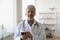 Portrait of trusted old mature doctor with cellphone in hands.