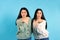 Portrait of twin girls who are sending an air kiss on a blue background in the same clothes.