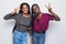 Portrait of a two african girlfriends showing two fingers sign on gray background