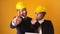 Portrait Of Two Architects Wearing Yellow Hard Hats Showing Thumbs-Up