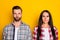 Portrait of two attractive content people partners wearing checked shirts isolated over bright yellow color background