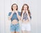 Portrait of two beautiful fashionable girlfriends in denim shorts and striped t-shirt posing nex to the glass wall. Have positive