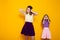 Portrait of two beautiful fashionable sisters of different ages on a yellow background