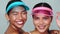 Portrait of two beautiful happy Asian women in sun visor cap smiling looking at the camera over white