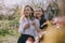 Portrait of two beautiful young sisters in the green spring garden, hugging in the field in the sunshine. Having fun together,