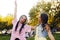 Portrait of a two brunette in a park at a festival. A two sister friends in pink dance.  Girls posing, dancing, smiling on a